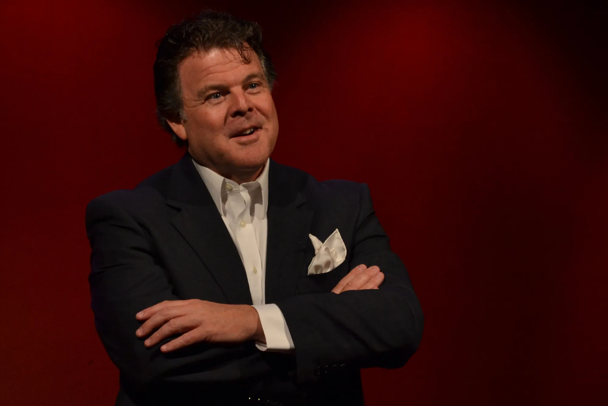 John Carney onstage speaking arms crossed