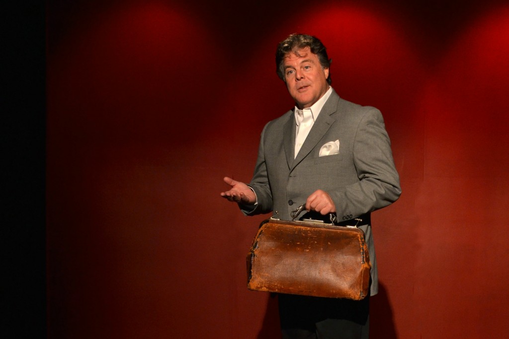 John onstage with a leather satchel